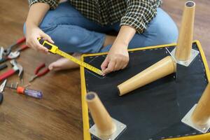 Asian Woman self repairs furniture renovation using equipment to diy repairing furniture sitting on the floor at home photo