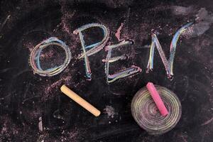 open written on a blackboard with a pink marker photo