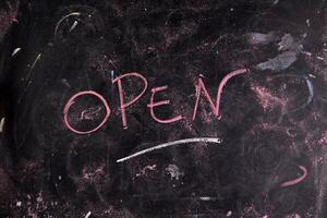 open written on a blackboard with a pink marker photo