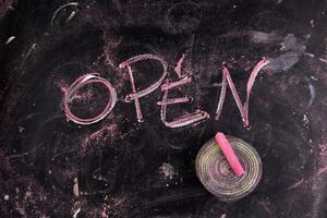 open written on a blackboard with a pink marker photo