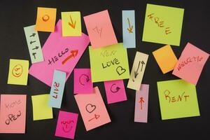 many colorful sticky notes are arranged on a black surface photo