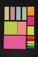 many colorful sticky notes are arranged on a black surface photo