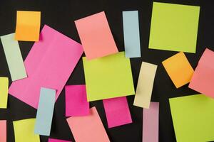 many colorful sticky notes are arranged on a black surface photo
