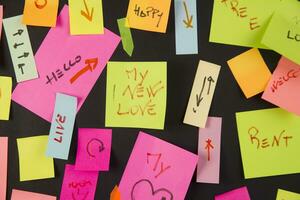 many colorful sticky notes are arranged on a black surface photo