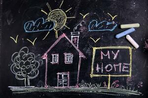 a chalkboard with a house, a sign and a sun photo