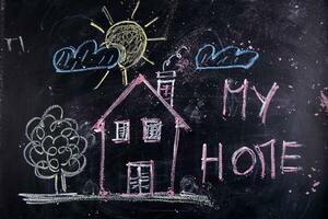 a chalkboard with a house, a sign and a sun photo