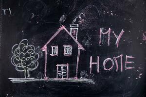 a chalkboard with a house, a sign and a sun photo