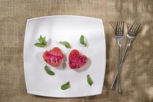 a white plate with a heart shaped piece of watermelon and a fork photo