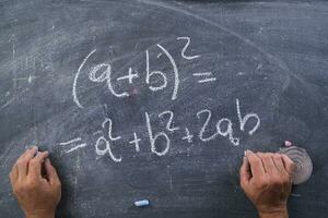 hands writing on a blackboard with math equations photo