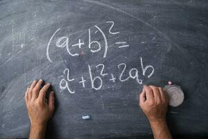 hands writing on a blackboard with math equations photo