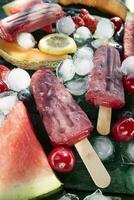 Popsicle made from red fruit on varied fruit table photo