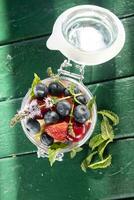 Colorful mixed fruit salad in glass container in green background. photo