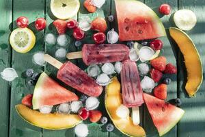 Popsicle made from red fruit on varied fruit table photo