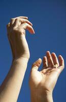 Female hands in the blue sky in the backlight photo