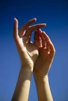 Female hands in the blue sky in the backlight photo