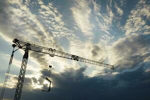 The profile of a construction crane at sunset photo