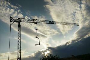 el perfil de un construcción grua a puesta de sol foto