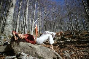 hermosa niña leyendo en el bosque en el otoño hora foto