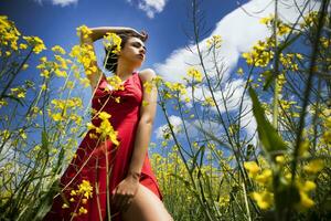 Young girl dressed in red in a field of yellow flowers photo