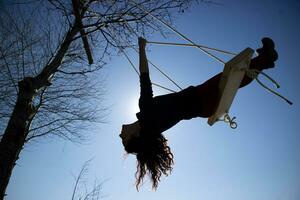 Girl shot against the light while having fun on the swing photo