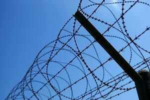 a barbed wire fence with a blue sky in the background photo