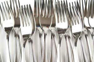 many forks and knives are arranged in a pile photo