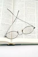 a pair of glasses is sitting on top of an open book photo