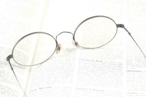 un par de lentes es sentado en parte superior de un abierto libro foto