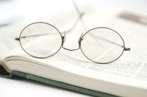 un par de lentes es sentado en parte superior de un abierto libro foto