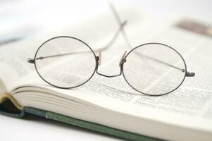 un par de lentes es sentado en parte superior de un abierto libro foto