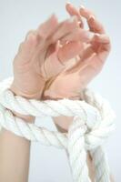 un mujer manos son atado a un cuerda foto