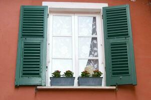 a window with shutters on a red wall photo