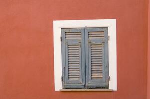 a window with shutters on a red wall photo