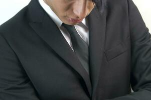 a man in a black suit and tie looking down photo