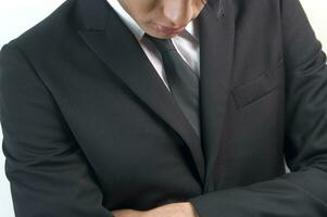 a man in a black suit and tie looking down photo