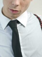 a man in a black suit and tie looking down photo