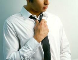 a man in a suit and tie standing against a wall photo