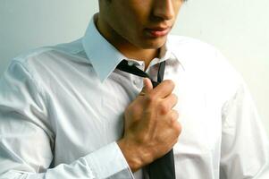 a man in a suit and tie standing against a wall photo