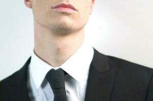 a man in a suit and tie standing against a wall photo