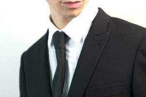 a man in a suit and tie standing against a wall photo