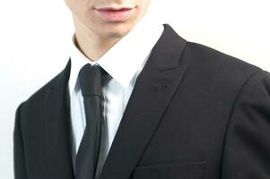 a man in a suit and tie standing against a wall photo