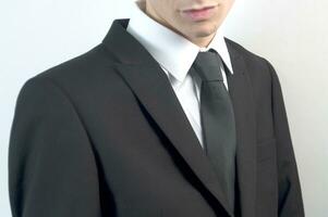 a man in a suit and tie standing against a wall photo