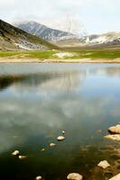 a person sitting on a rock near a lake photo