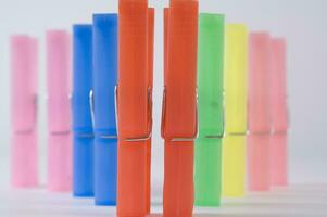 a pile of colorful clothes pegs on a white surface photo