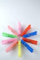 a pile of colorful clothes pegs on a white surface photo