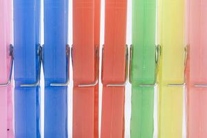 a pile of colorful clothes pegs on a white surface photo