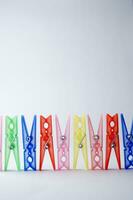 a pile of colorful clothes pegs on a white surface photo