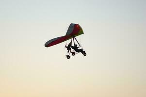 a person flying a hang glider in the sky photo