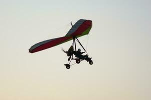 a person flying a hang glider in the sky photo