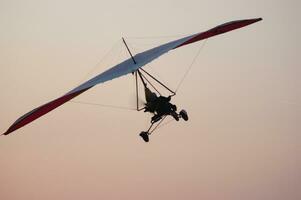 a person flying a hang glider in the sky photo